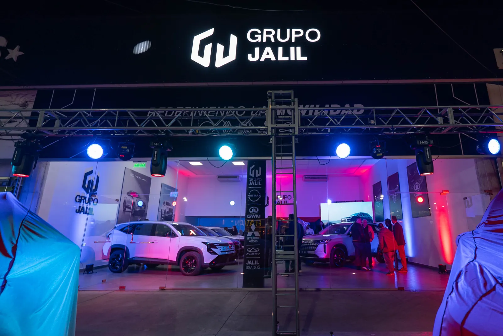Fachada iluminada del concesionario de Grupo Jalil de noche, con el cartel y el lema Redefiniendo la movilidad