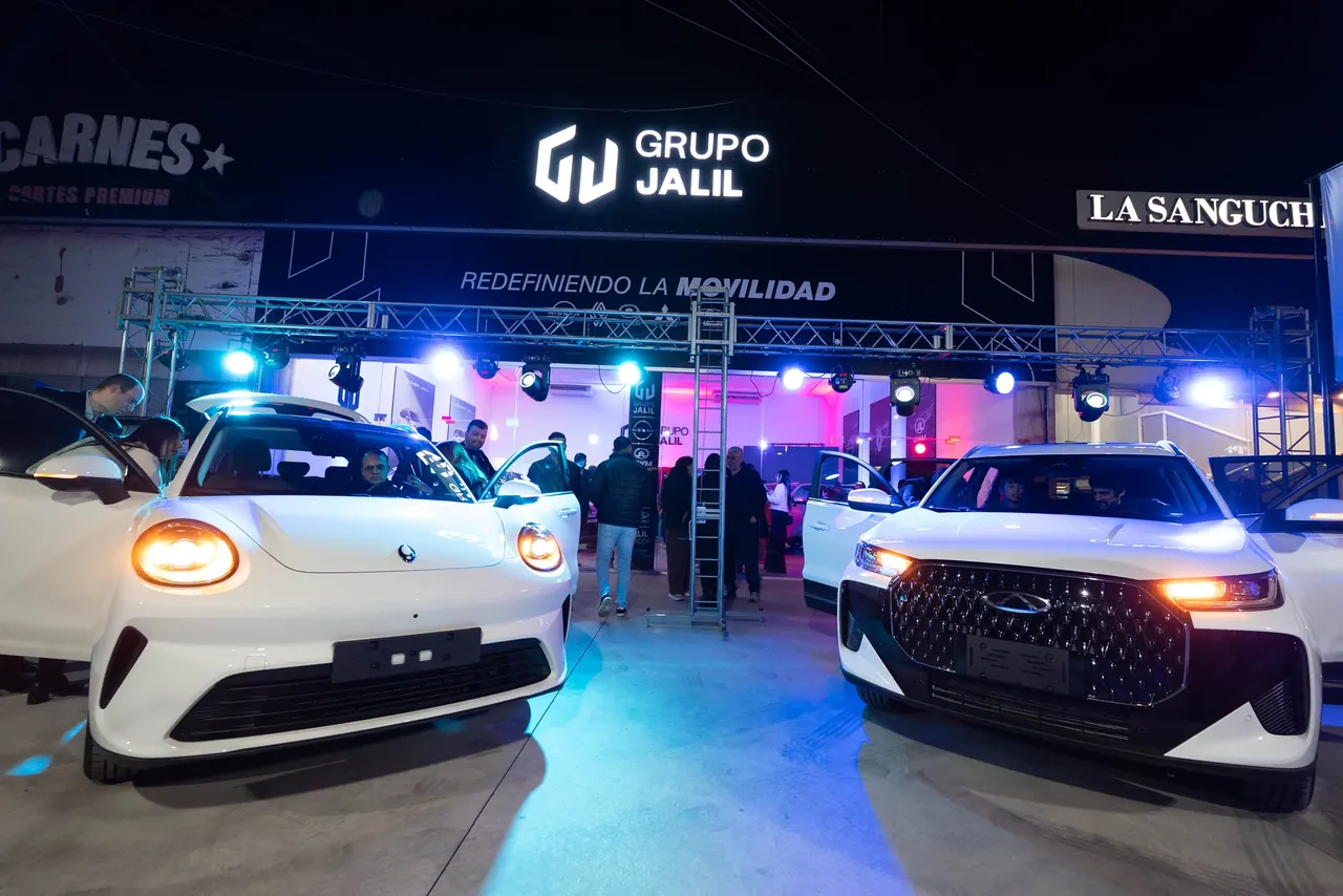 Dos autos en el stand de Grupo Jalil de noche, con el cartel y el lema Redefiniendo la movilidad